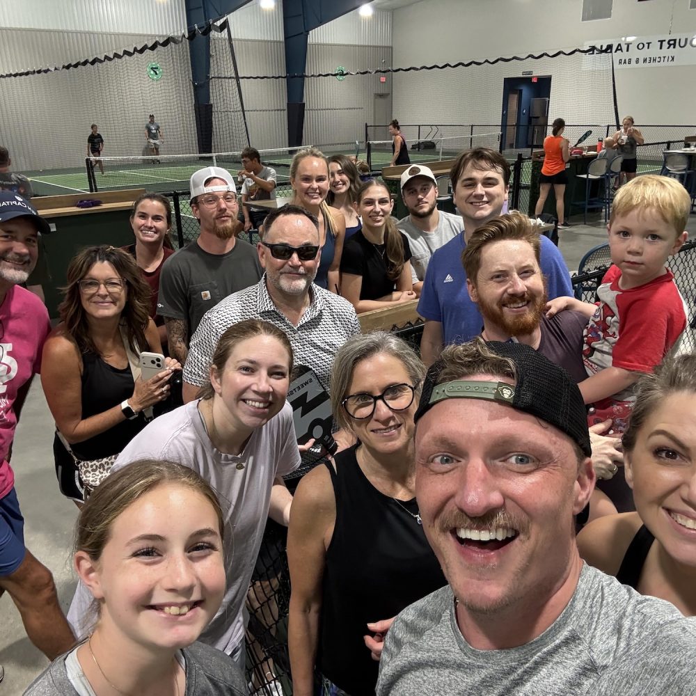 connect outside your routine | Crossroads Counseling staff group photo at an indoor pickleball court after a team-building outing